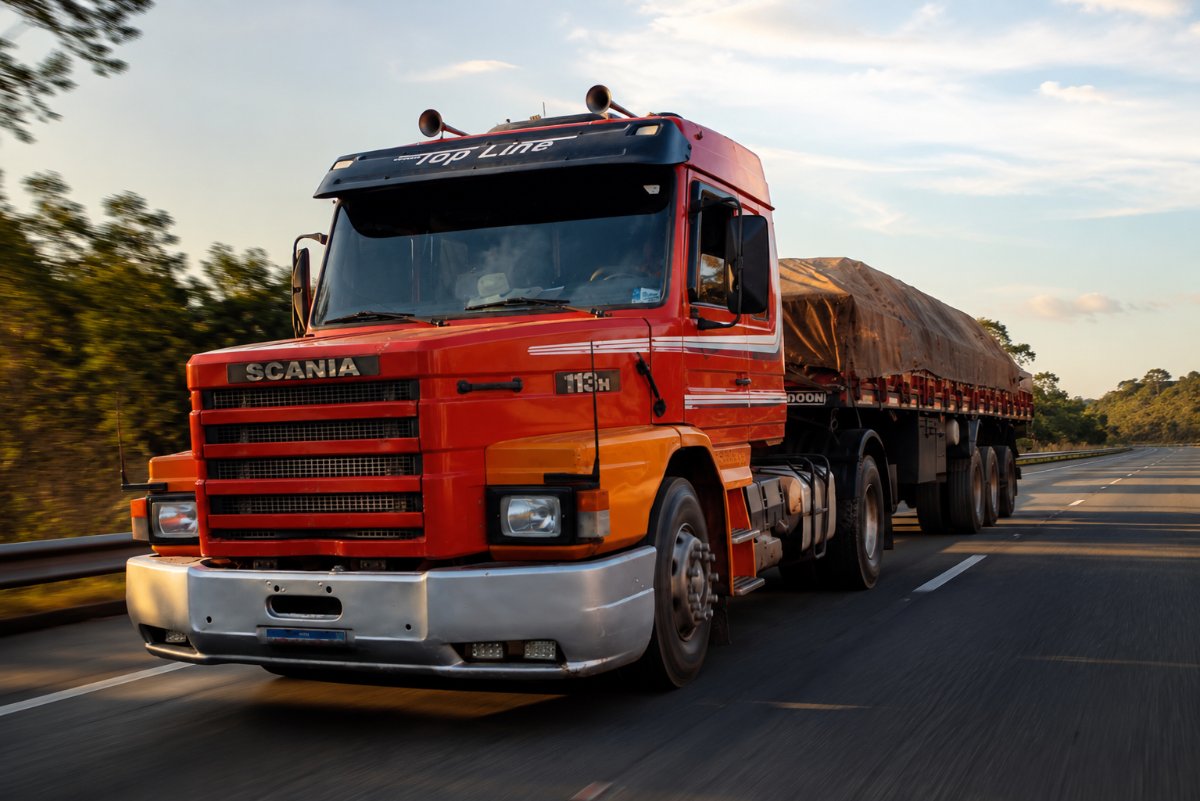 Caminhão Scania vermelho da frota Trans Bala com contêiner em rodovia